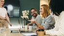 Business woman talking to her colleagues during a meeting in a boardroom. Group of happy business people working together in a creative office.