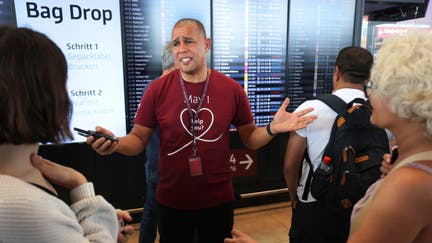 Airport employee Derek Bangura speaks to anxious travellers at BER Berlin Airport during an IT outage that has disrupted airline services worldwide on July 19, 2024 in Schoenefeld, Germany. Businesses, travel companies and Microsoft users across the globe were among those affected by a tech outage today. 
