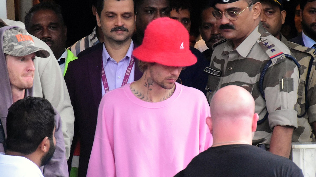 Justin Bieber wearing a red bucket hat and pink sweater in a crowd