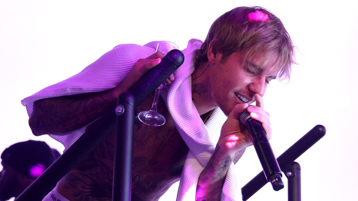 Justin Bieber leans over and sings into the microphone in Hollywood
