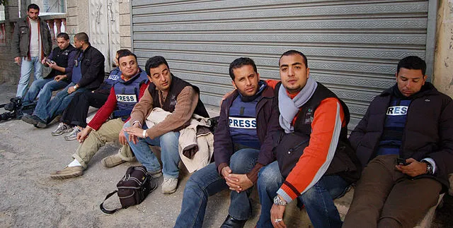 Al-Jazeera journalists in Gaza sit outside their offices following concerns that the military could