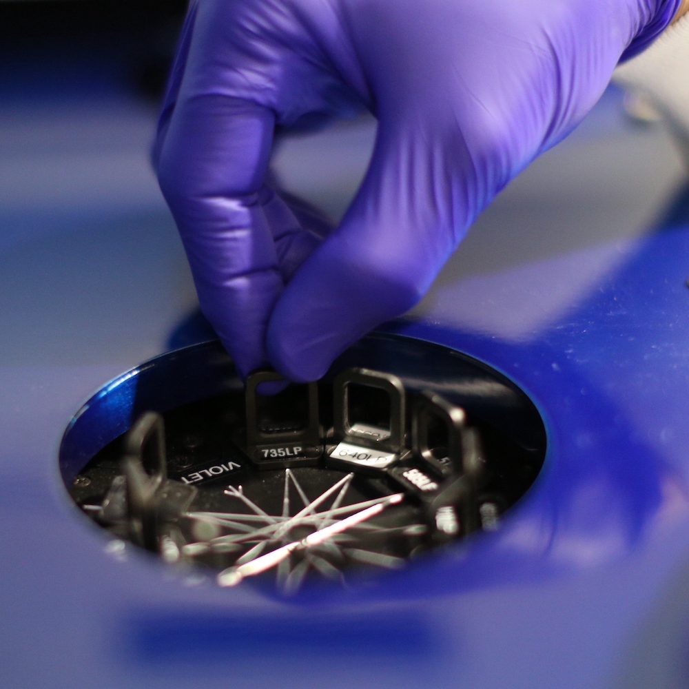 Gloved hand reaching into robot for an immunology experiment at the Allen Institute