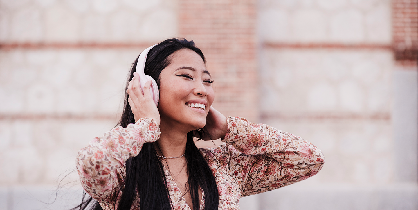 Beautiful woman enjoying music over headphones by wall