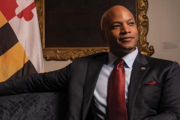 Governor Wes Moore sits in front of a Maryland flag