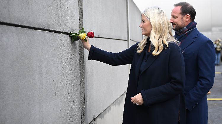 Das Paar steckte ein paar Blumen in die Überreste der Berliner Mauer.