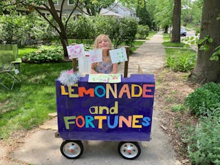 Willa reveals fortunes on the other side of colorful art she hangs above her lemonade stand. Minneapolis lemonade seller, 7, adds artful fortune-telli