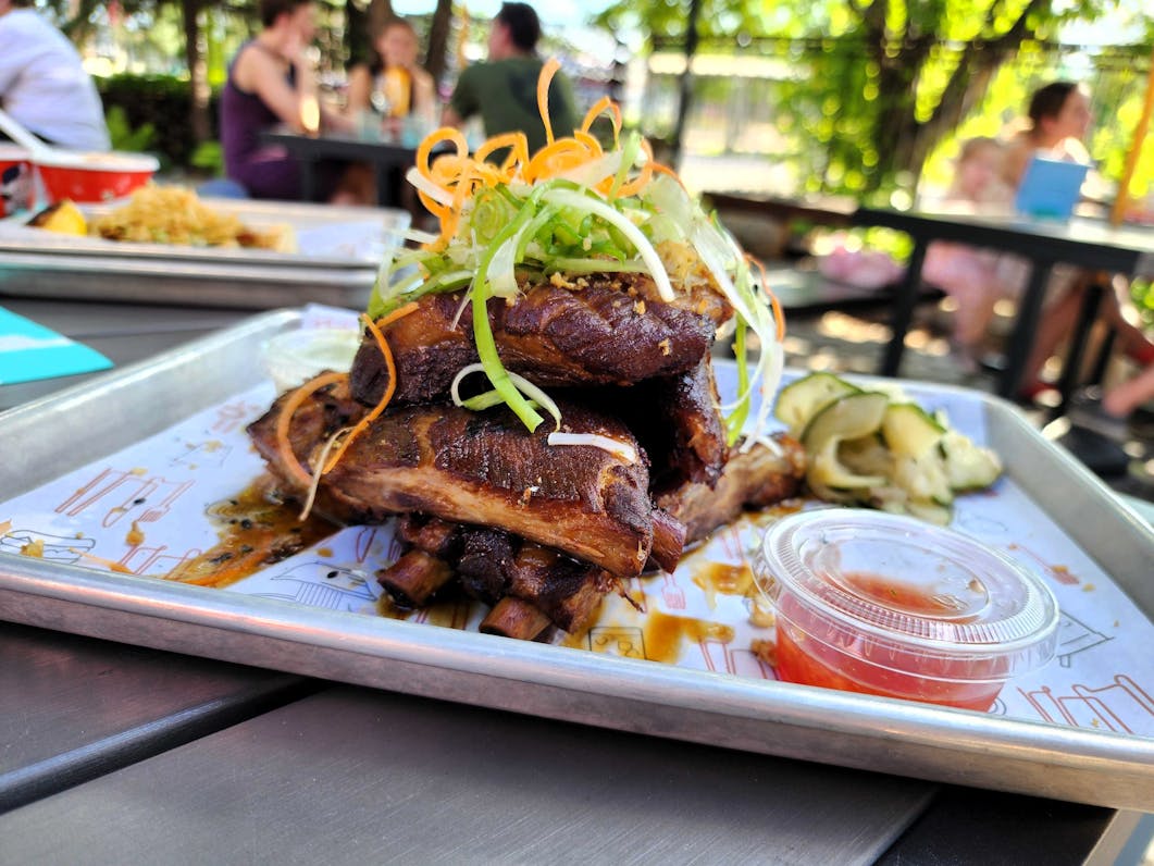 A tray with a stack of ribs piled high, shaved scallion greens on top