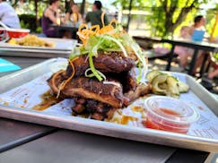 A tray with a stack of ribs piled high, shaved scallion greens on top