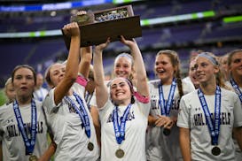 Holy Angels player celebrate with their trophy after defeating Mahtomedi in the girls' Class 2A soccer state championship gam.