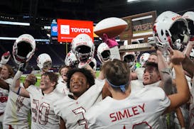 Simley Spartans teammates, including Simley Spartans running back David Gogins (3) and Simley Spartans quarterback Caden Renslow (10), ran to the fan 