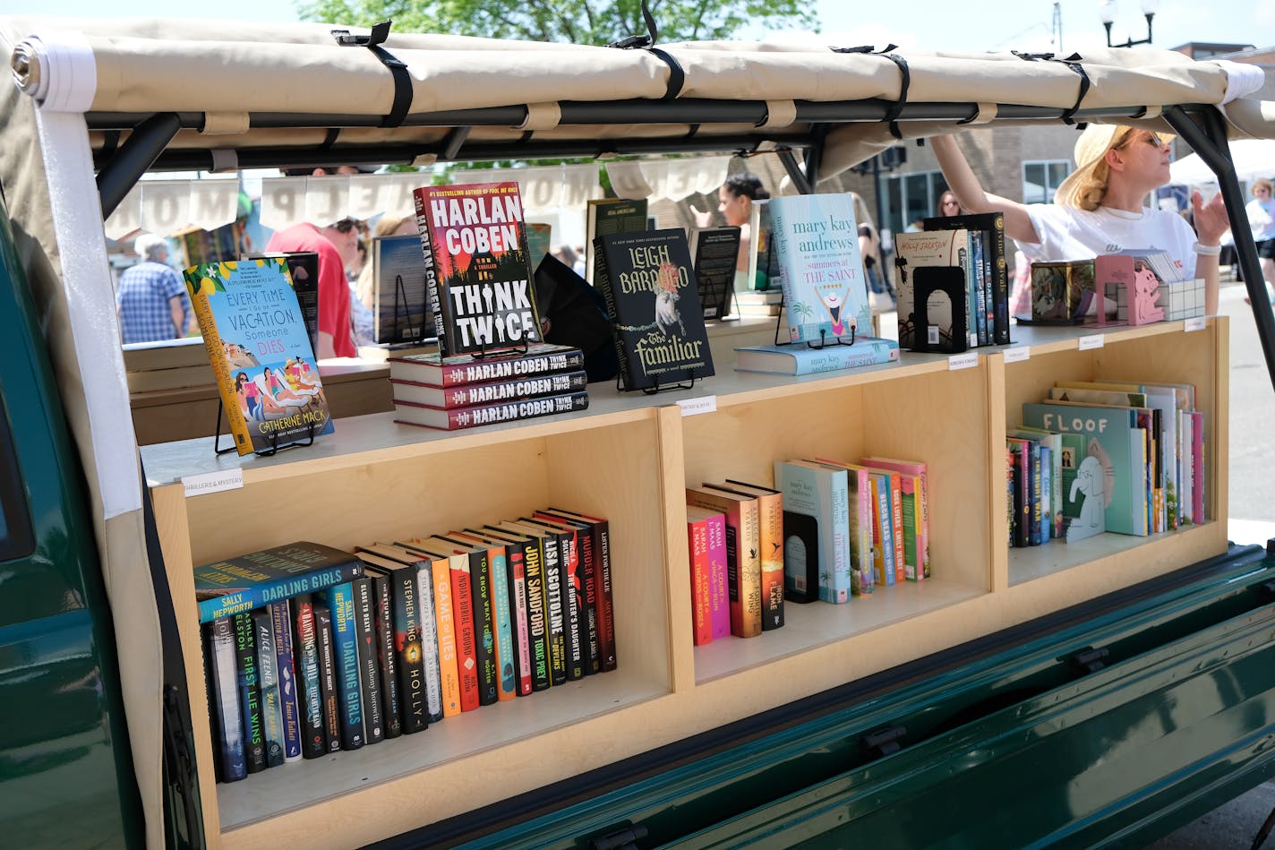 photo of bookshelves on the back of a truck, with a woman at the rear of the truck