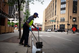 Downtown safety captain Travion Thompson with the St. Paul Downtown Alliance picks up trash while on patrol in St. Paul on June 11.