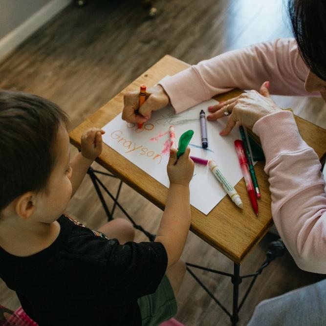 		Two people color with markers at a small table
	