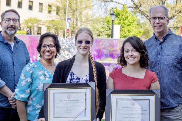 Award winners holding framed certificates smiling at the camera with other people next to them also smiling