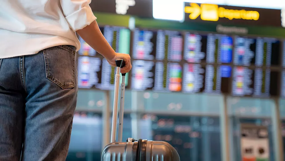 Insured person traveling holding suitcase in an airport.