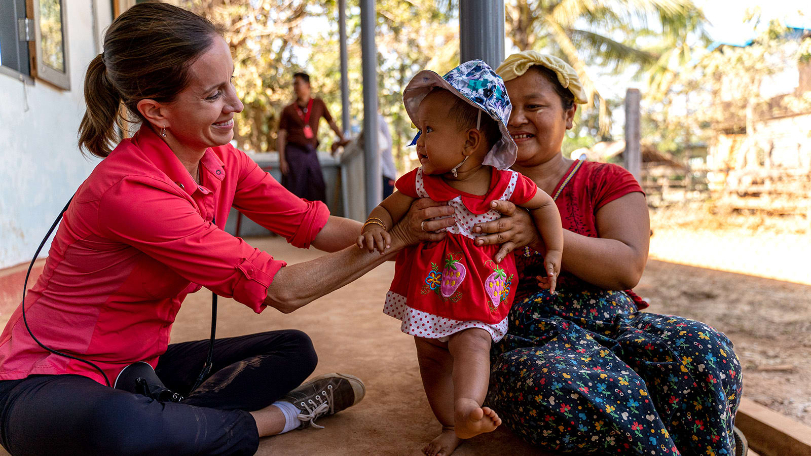 two women carrying a baby and smile