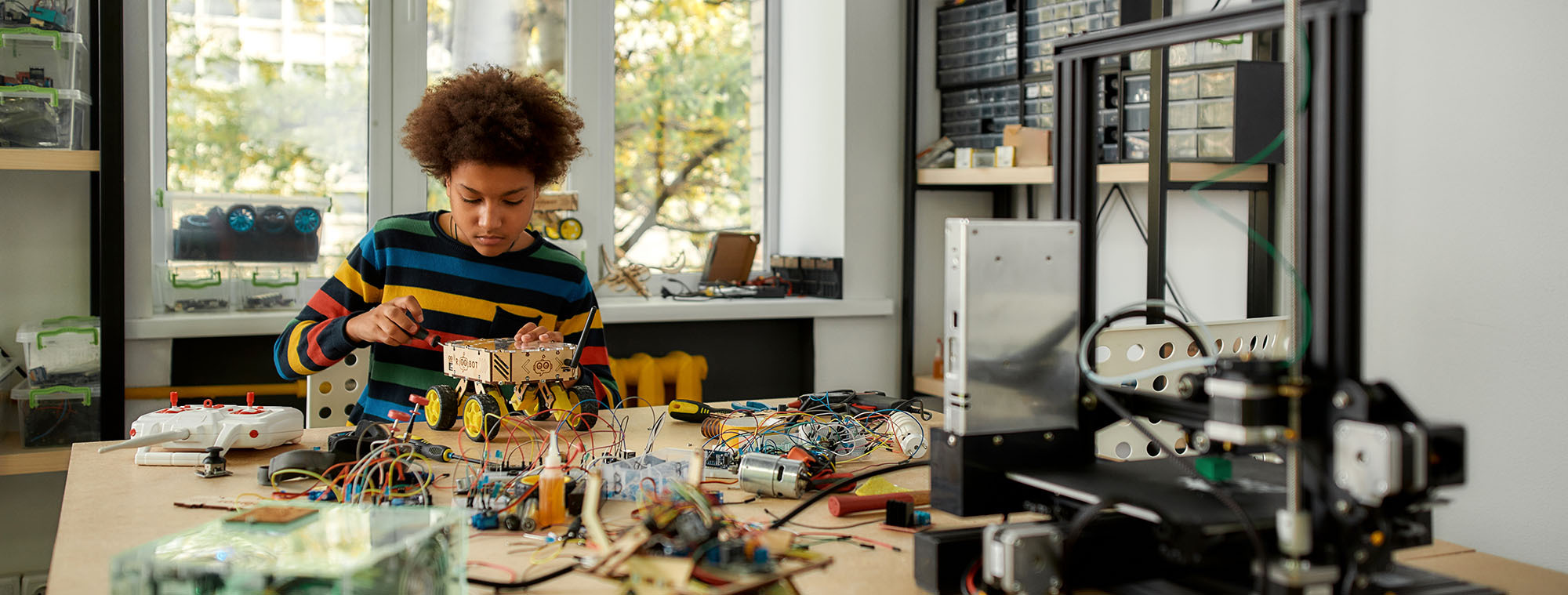 A teen works on a robotics project that appears to be a vehicle 