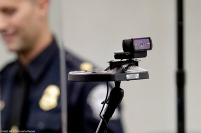 A face recognition camera with a CBP agent in the background.