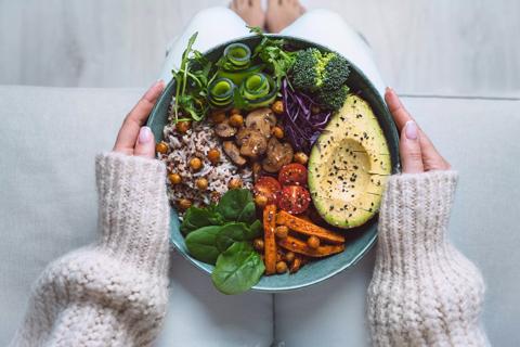 Person holding a plate of veggies and rice on their lap