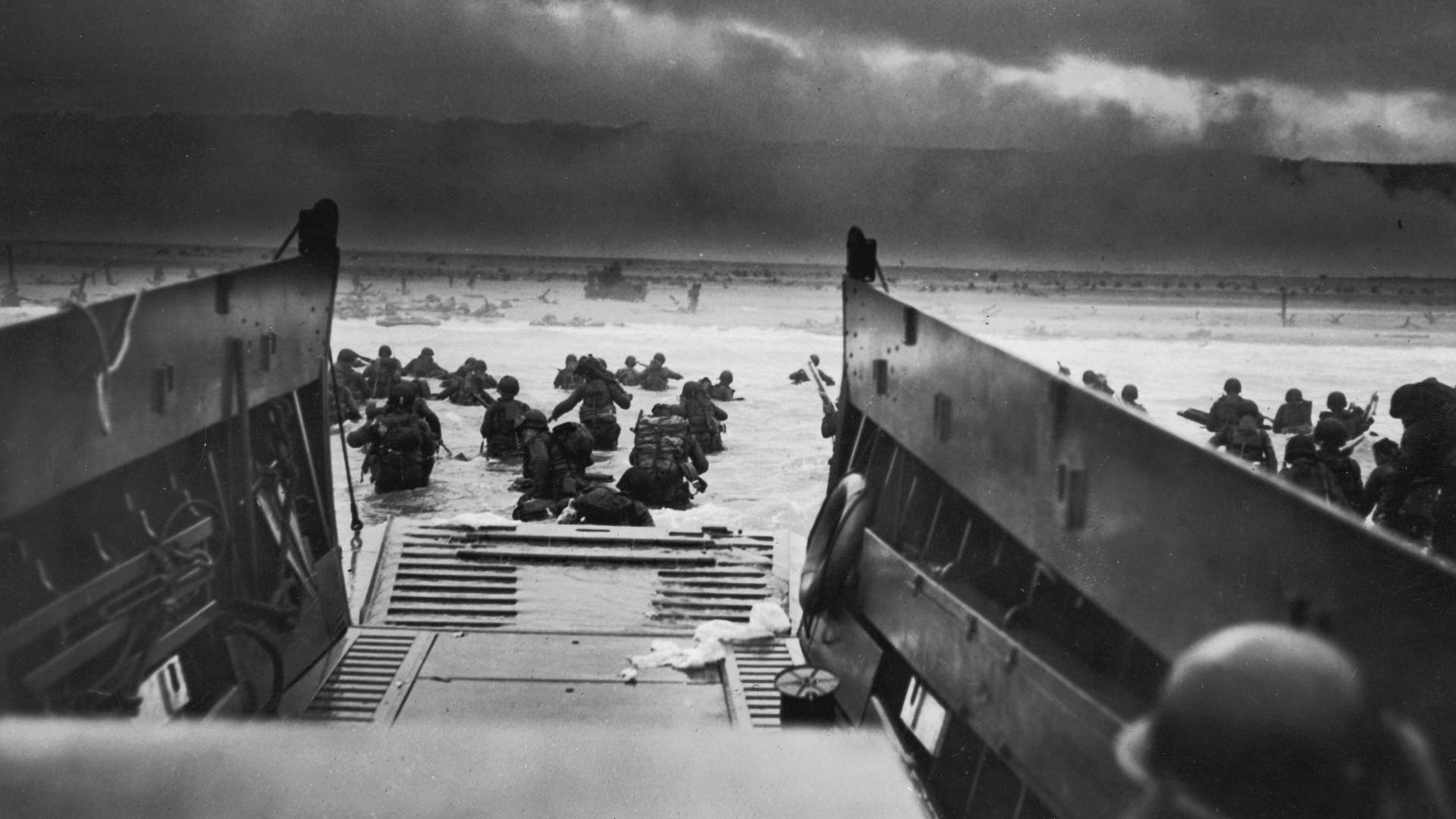 D-Day Landings: A view from inside one of the landing craft after US troops hit the water during the Allied D-Day invasion of Normandy, France. The US troops on the shore are lying flat under German machine gun resistance.