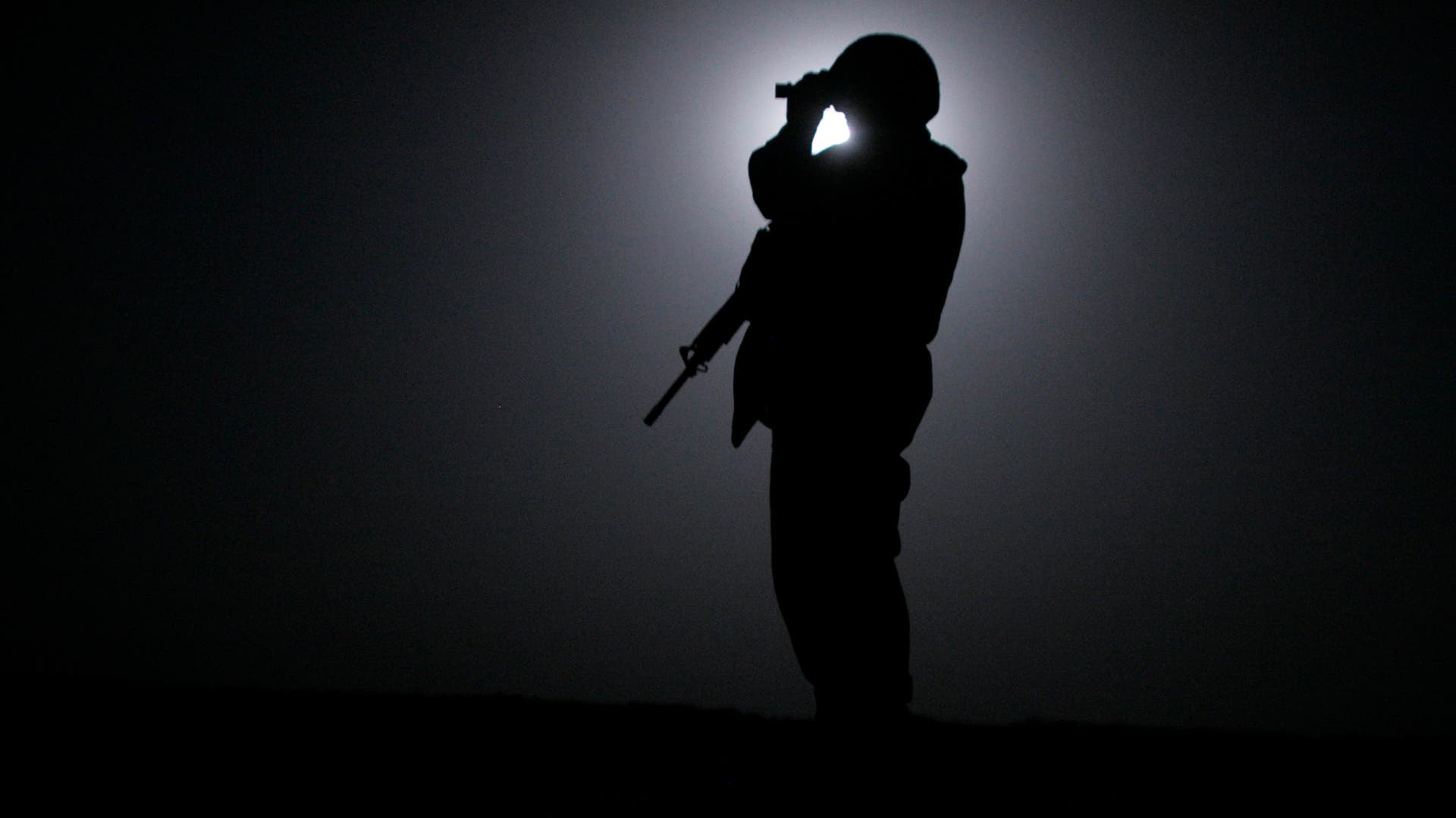 A Marine from the 3rd Battalion, Fourth Marines scans the horizon with night vision goggles while silhouetted by the moon during midnight patrol around Camp Mercury, the former Camp Abu Ghraib, June 23, 2005 in Anbar province, Iraq.