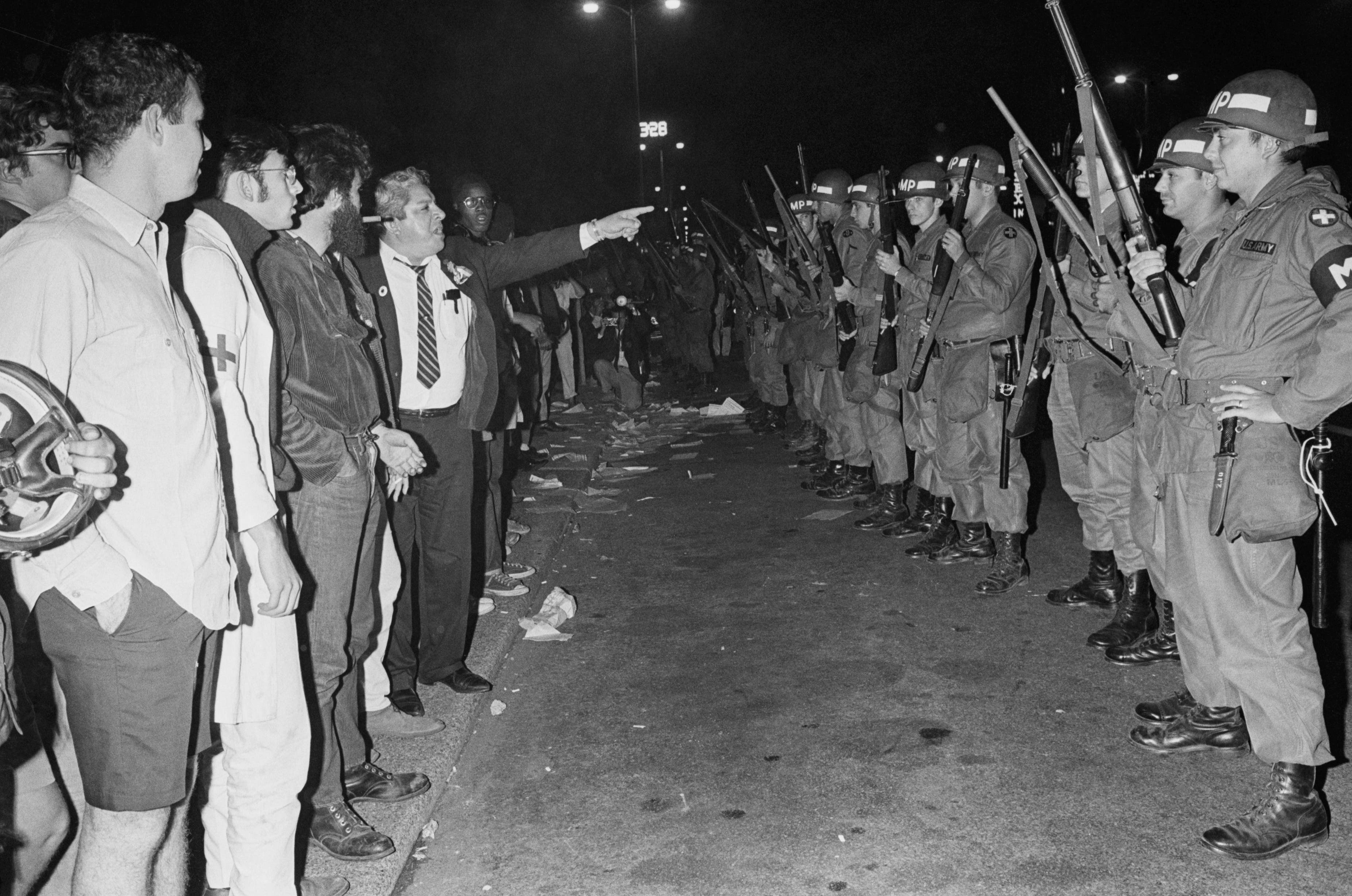 (Original Caption) Chicago, IL: An unidentified bystander points accusingly at Illinois National Guardsmen as they stand guard of Grant Park early 8/28 following a large scale confrontation with hippies. Seven hundred troops, all members of the 33rd MP battalion, were ordered into the park, across the street from Democratic National Convention Headquarters at the Conrad Hotel. 8/28/1968