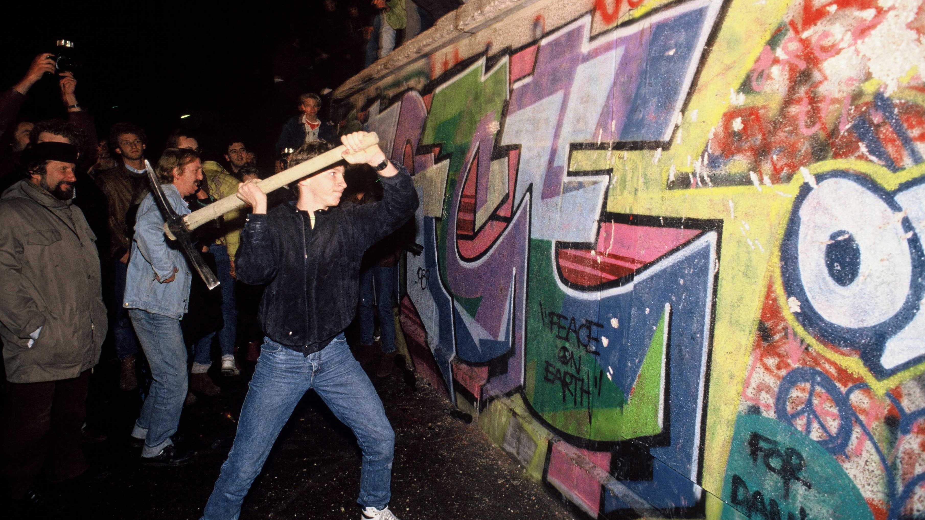 A man attacks the Berlin Wall in 1989.