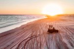 people watch the sunset by a 4x4 on the beach