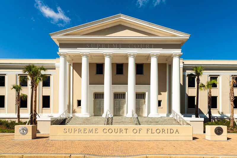 Beige and white columned building with palm trees. A sign at the bottom reads Supreme Court of Florida