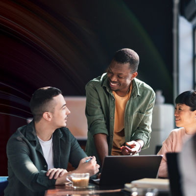 People at a desk talking and working on a laptop