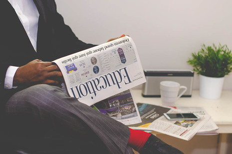 Man sitting, reading a newspaper