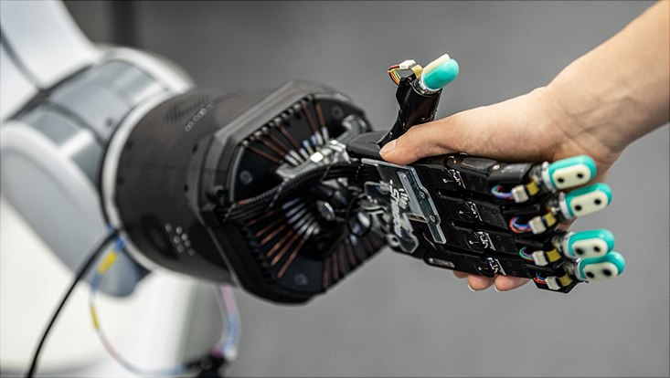 Ein Mensch reicht einem Roboter die Hand zum Handschlag.