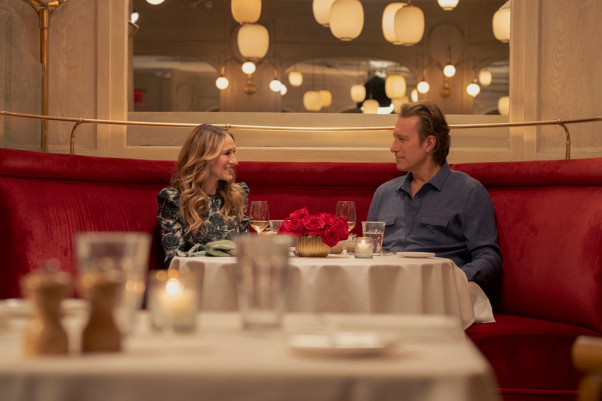 Carrie and Aiden sit in a booth at Benoit—a Michelin starred New York restaurant in Midtown.