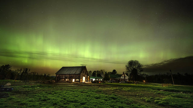 The northern lights fill the sky with green over the barn and pastures at Greaney's Turkey Farm in Mercer, Maine, on May 11, 2024. 