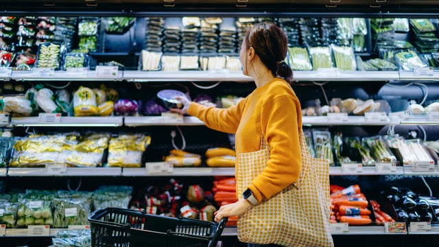 Young Asian woman with shopping cart, carrying a reusable shopping bag, shopping for fresh organic fruits and vegetables in supermarket. Environmentally friendly concept. Zero waste and plastic free. Eco friendly shopping. Sustainable living lifestyle 