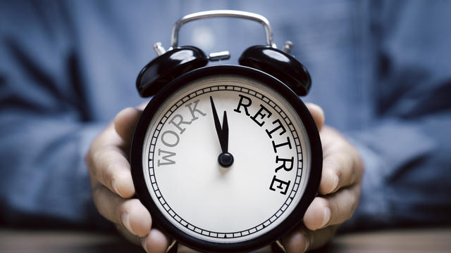 Businessman holding black alarm clock with clockwise countdown from work to retirement. 