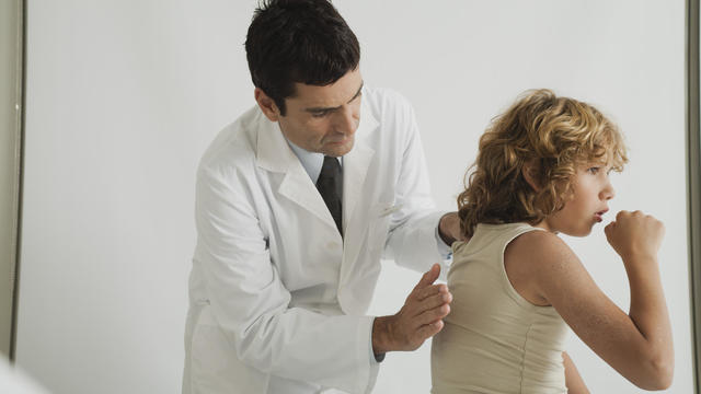 Doctor checking young patient's cough 