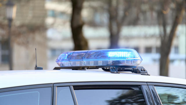 a close-up view of a police vehicle with blue lights patrolling near a public park with the windows and doors closed 