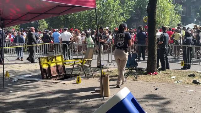 Evidence markers on the ground in Brooklyn with a large crowd in the background. 