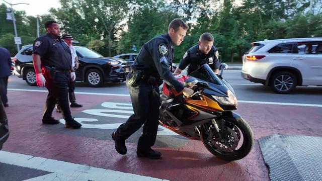 Two NYPD officers load a motorcycle into the back of a truck on a Staten Island street. 