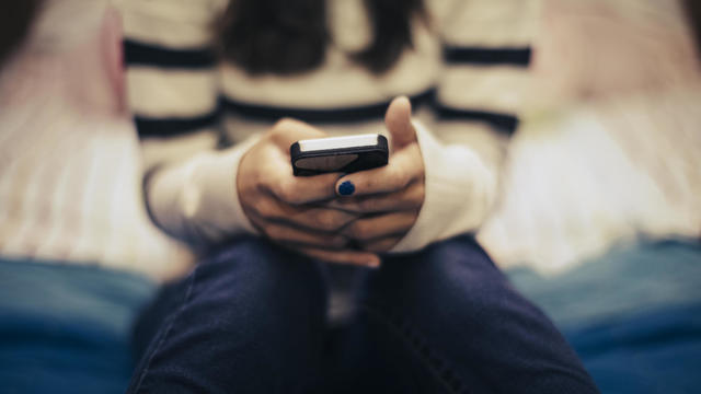 Close up of teenage girl in bedroom using smart phone 