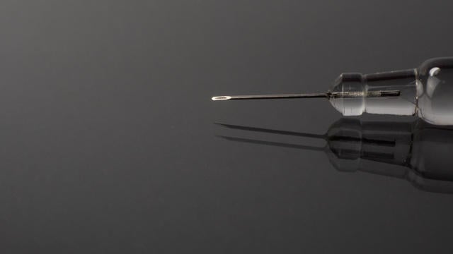 Syringe with fine needle reflected on a gray background with mirror effect 