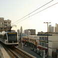 los angeles metro train rolls into a station with downtown la in the background