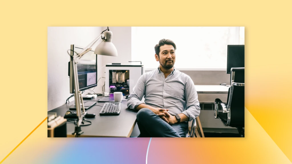 a man sits at a desk with multiple computer monitors