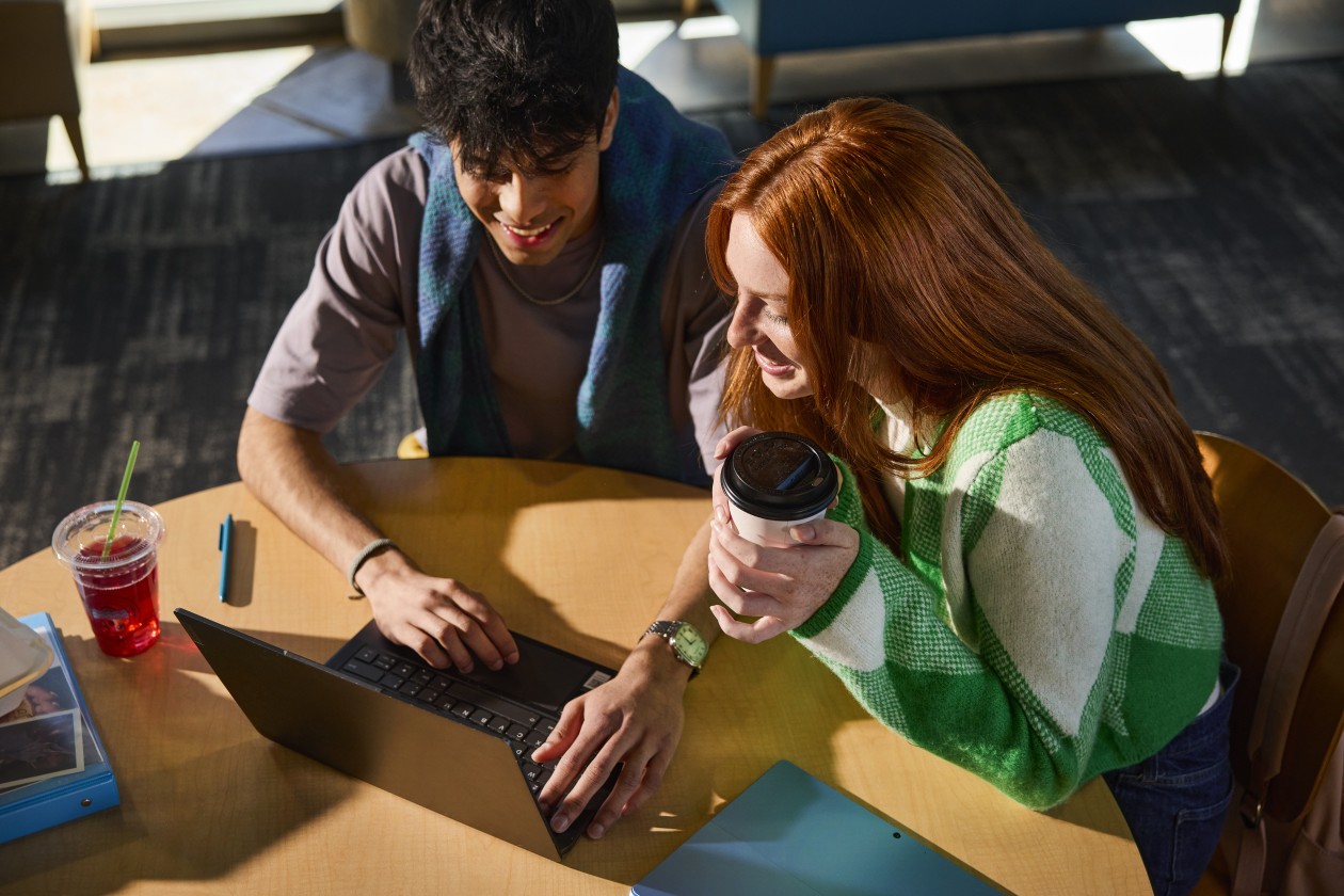 Two people sitting at table on laptop