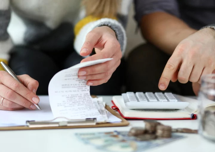 Imagem de um casal fazendo contas com uma calculadora e caderno em cima de uma mesa para ilustrar matéria sobre o que é IPCA