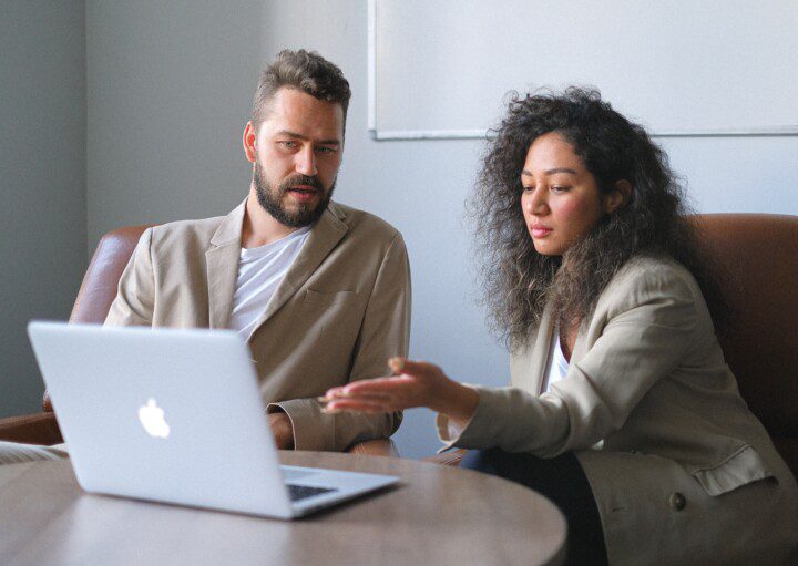 A foto que ilustra a matéria sobre como vender apartamento financiado mostra duas pessoas (um homem e uma mulher) diante de um computador pesquisando.