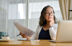 Mulher asiática de meia idade concentrada usando notebook.