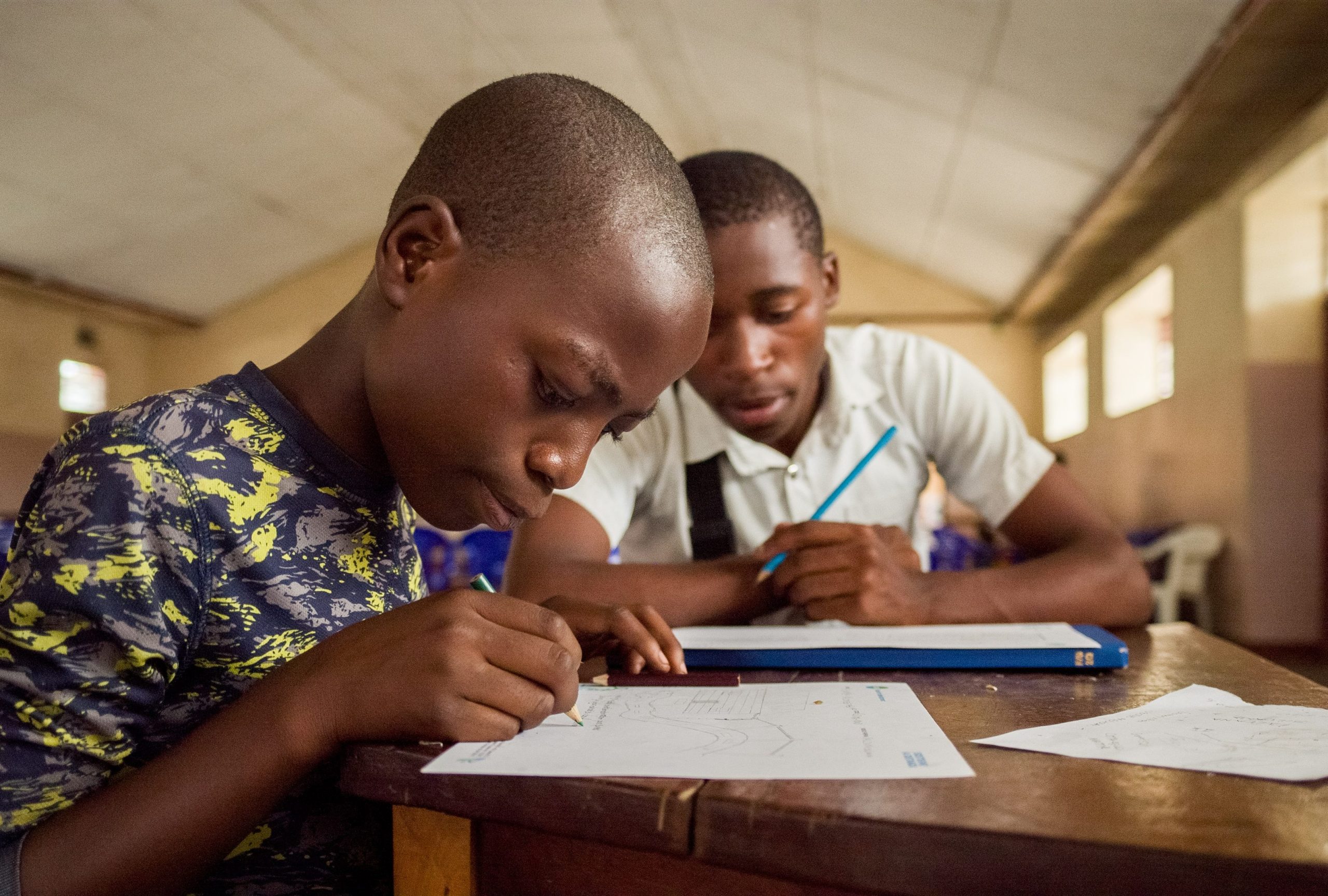 A Burundian child in Democratic Republic of the Congo studying with his teacher