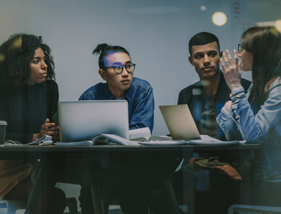 group of young adults talking around a laptop